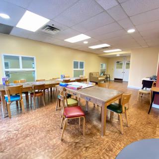 An empty classroom with tables and chairs arranged neatly.