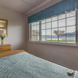 A serene bedroom with a beautiful view of the ocean, featuring natural light and floral decor.