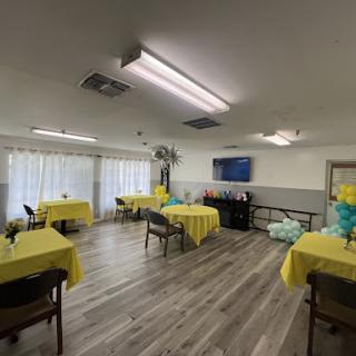 A bright and inviting event space, set up with yellow tablecloths and decorative balloons, perfect for gatherings.