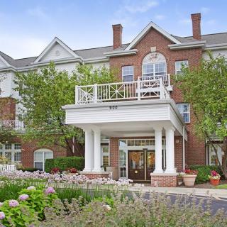A residential building with a grand entrance, featuring white columns and surrounded by greenery.