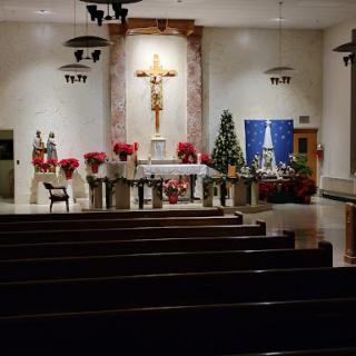 A beautifully decorated church altar for the Christmas season, featuring festive floral arrangements and a prominent cross.