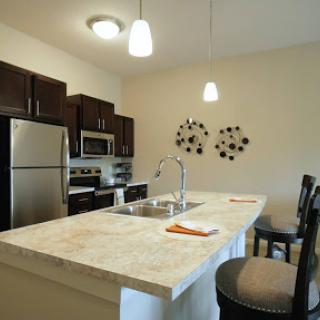 A modern kitchen featuring dark cabinetry and a spacious island with barstools.