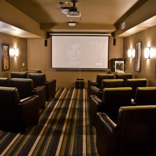 A cozy home theater setup with comfortable recliner seating and a large projector screen, perfect for movie nights.