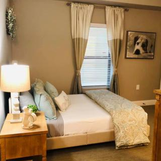 A cozy and well-decorated bedroom with a neatly made bed, side table with a lamp, and artwork on the wall.