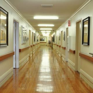 A well-lit hospital corridor with polished floors and artwork on the walls.