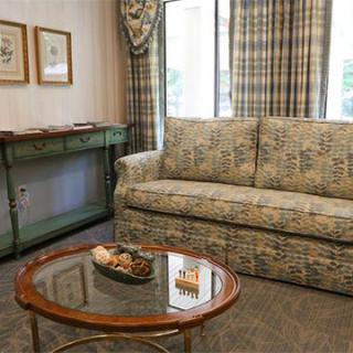 A cozy living room with a patterned sofa, a round glass coffee table, and decorative artwork on the walls.