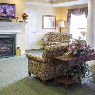 A cozy living room with patterned sofas, a coffee table with flowers, and a fireplace under a mounted television.
