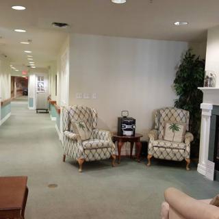 A cozy lobby area with patterned chairs, a small table, and a fireplace along a hallway.