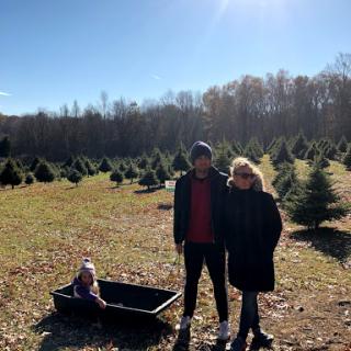 A family enjoying a sunny day at a Christmas tree farm.