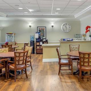 A cozy dining room with wooden tables and chairs arranged neatly on a hardwood floor.