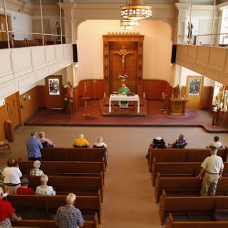 A serene view of a church interior during a worship service, showcasing the congregation gathered in prayer.