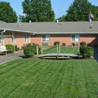 A neatly maintained lawn with a small wooden bridge and surrounding landscaping in an outdoor courtyard.