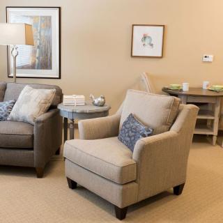 A cozy living room with modern decor featuring a sofa, armchair, and side tables.