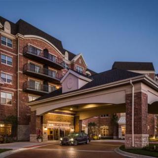 A luxurious hotel entrance with a car parked under the portico during the evening.