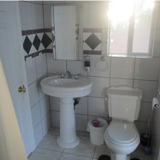 A small bathroom with a pedestal sink, toilet, and tiled walls.