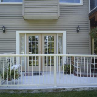 A house exterior featuring a patio with French doors and a white railing.