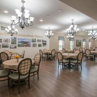A well-lit dining area featuring elegant chandeliers and neatly arranged tables with chairs.