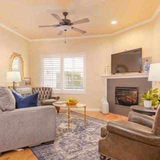 A cozy living room with a sofa, armchairs, and a fireplace, featuring a TV above the mantel.