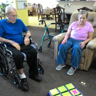 Two elderly individuals engaging with a puzzle game in a care facility.