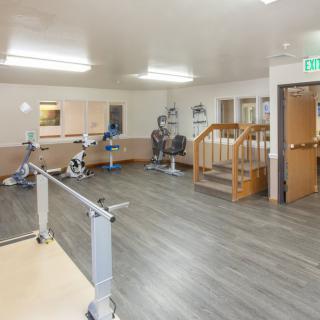 A spacious gym area equipped with exercise bikes and parallel bars for rehabilitation.
