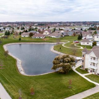 Aerial view of a residential neighborhood with a central lake and surrounding houses.