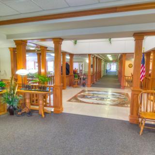 A spacious lobby with wooden columns, decorative plants, and an American flag.