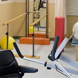 A physical therapy room equipped with parallel bars and other rehabilitation equipment.