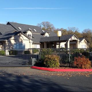 A large residential building with a fenced entrance and surrounding trees.