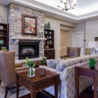 A cozy living room featuring a stone fireplace, elegant furniture, and tasteful decor.