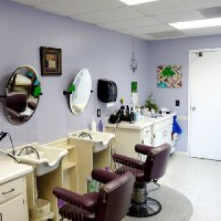 A tidy barber shop interior with purple walls, featuring two chairs and mirrors.