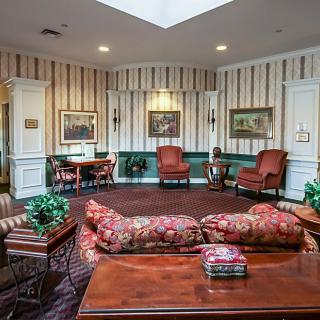 A traditional living room with striped wallpaper, featuring a sofa, armchairs, a coffee table, and framed artwork.