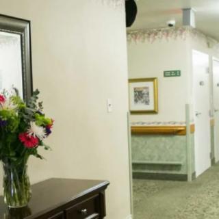 A hallway interior with a vase of flowers on a table and a mirror on the wall.