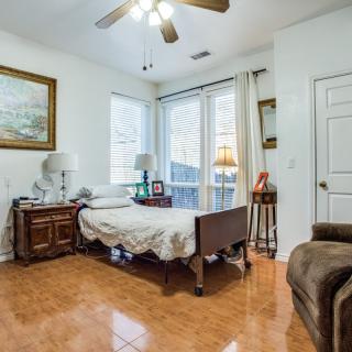 A cozy bedroom with a single bed, bedside table, and large windows allowing natural light in.