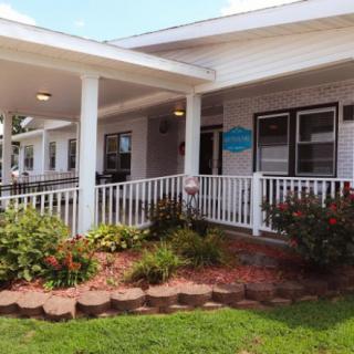 A single-story building with a white porch and well-maintained landscaping.
