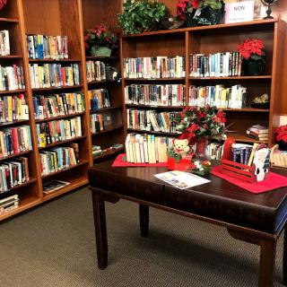 A cozy library corner with bookshelves and a table decorated for the holidays.