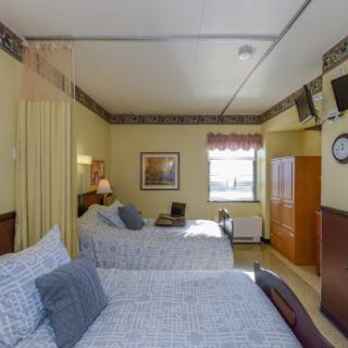 A cozy hotel room featuring two beds, warm lighting, and a view from the window.