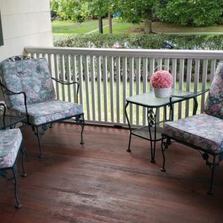 A cozy porch setup with cushioned chairs and a small table adorned with flowers.