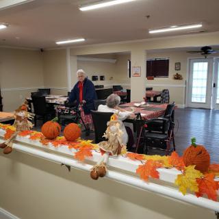 A vibrant autumn-themed setting in a community center, featuring festive decorations and an engaged resident.