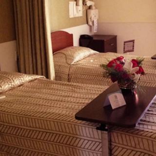 A hospital room with two beds, decorated with a flower arrangement on the bedside table.