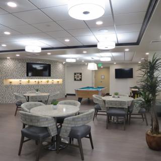 A modern lounge area with tables, chairs, a pool table, and television screens.