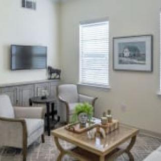 A cozy living room with armchairs, a coffee table, and a wall-mounted television.