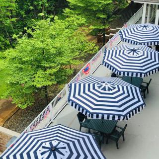 Aerial view of a patio with striped umbrellas and tables, surrounded by lush greenery.