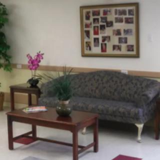 A cozy waiting room with a sofa, coffee table, and framed photos on the wall.