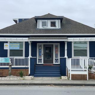 A blue residential house with a front porch and multiple windows.