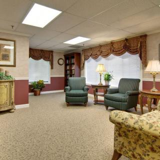 A cozy living room with traditional decor featuring armchairs, a carpet, and warm lighting.