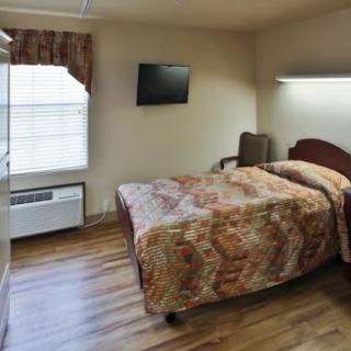 A cozy hotel room with a single bed, wall-mounted television, and wooden flooring.