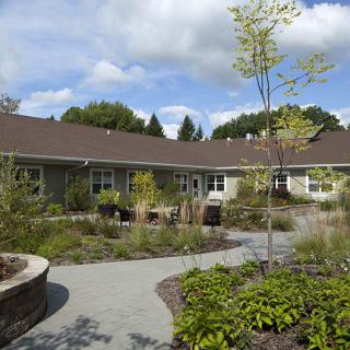A well-maintained garden with a pathway leading to a building under a partly cloudy sky.