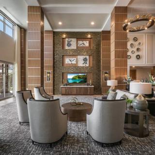 A modern and luxurious lobby featuring a seating area with elegant chairs, a television, and stylish artwork.