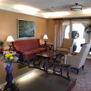A cozy living room with a red sofa, comfortable armchairs, and decorative elements like lamps and artwork.