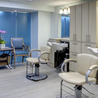 A modern hair salon interior with styling chairs, mirrors, and cabinetry.